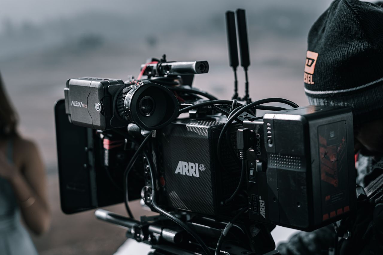 Home Close-up of a professional filmmaking camera setup on an outdoor set with blurred background.